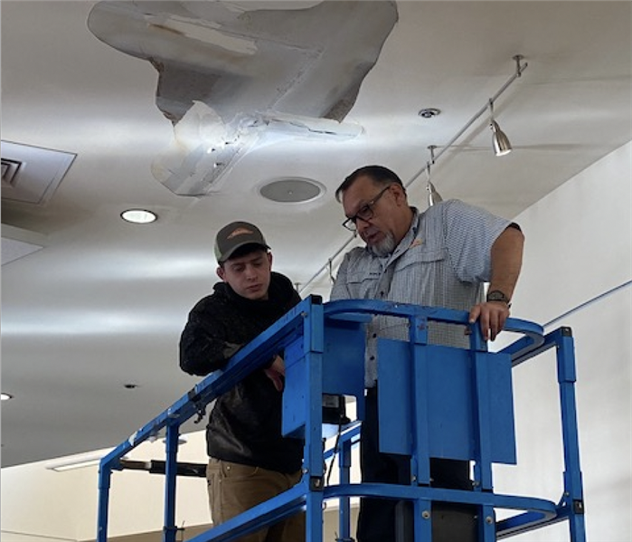 Team members on a lift working on a big ceiling leak.